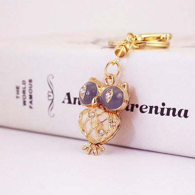 Angled front view of the gold-tone owl charm beside its split key ring.