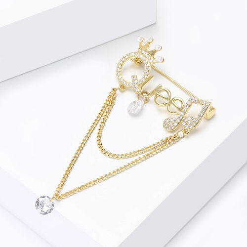 Angled display of the queen chain dangle brooch on a white surface