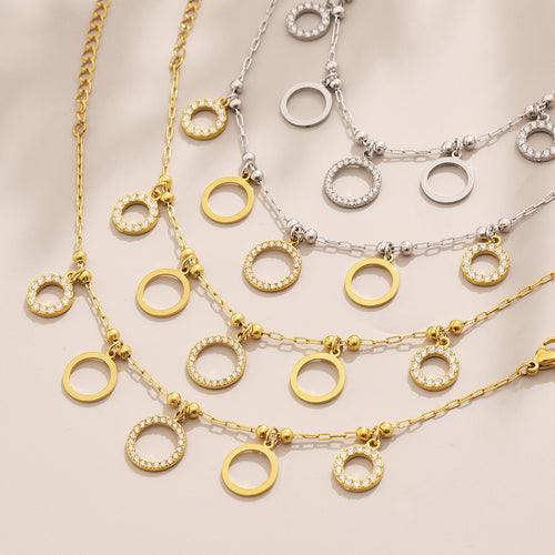 Flat lay of gold and silver circle pendant bracelets with zircon rings