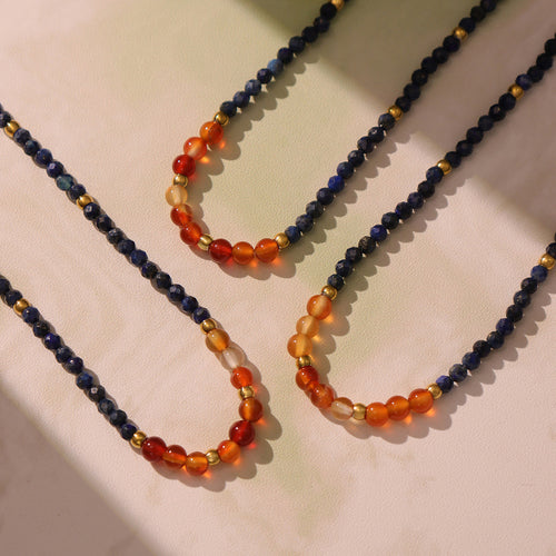 Several lapis and red agate bead strands on fabric