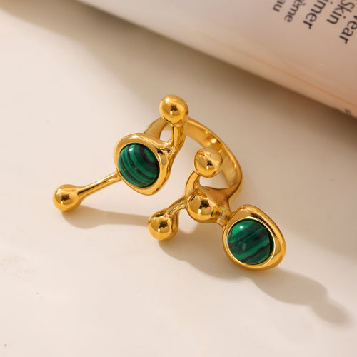 Two gold malachite abstract dual stone open rings on beige surface
