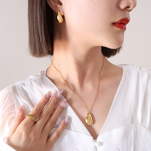 Gold teardrop pendant and matching stud earring worn white blouse