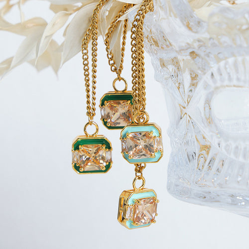 Green and blue enamel square crystal pendants hanging near glass vase