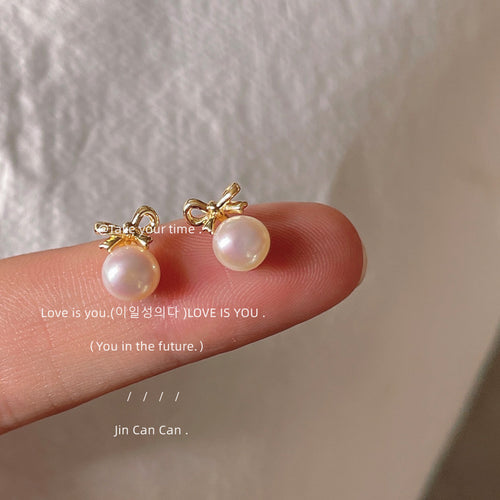 Gold-tone bow white-pearlescent drop studs in the first product display.