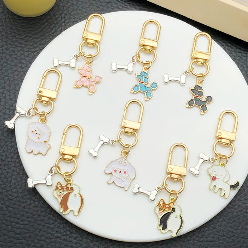 Grouped sixteen dog and bone enamel clasp keychains arranged together on a styled display surface