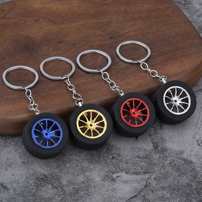 Four wheel-and-tire keychains display blue, gold-tone, red, and silver-tone multispoke rims.