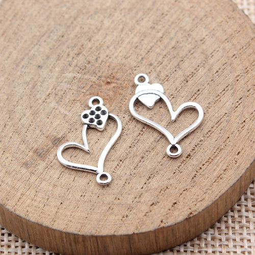 Antique Silver Open Heart Rhinestone Connectors for Jewelry Making arranged on a wood slice