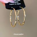 Gold Tone Twisted Oval Hoop Earrings with Detailed Finish view 2