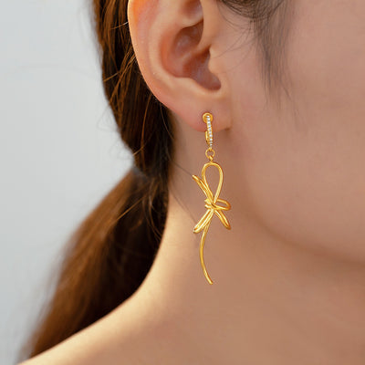 Gold bow knot drop earring with rhinestone huggie worn on ear