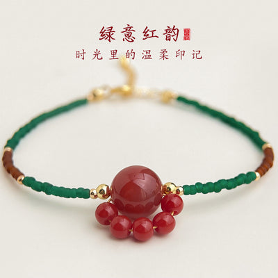 Green cord red cat paw focal bracelet on cream surface