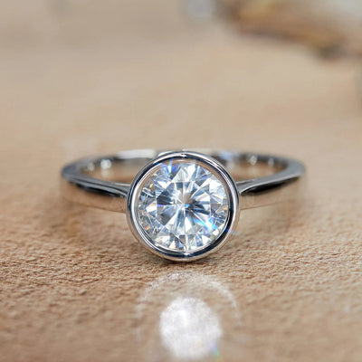 Product view showing silver-tone round clear solitaire bezel ring