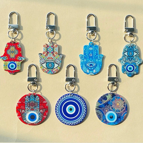 Seven assorted acrylic Hamsa and round evil eye keychains in sunlight