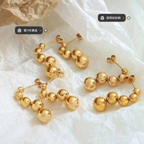 Gold ball drop stud earrings flat lay with plating and titanium steel labels