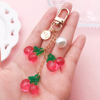 Image 1 showing a hand holding a pink and green strawberry keychain.