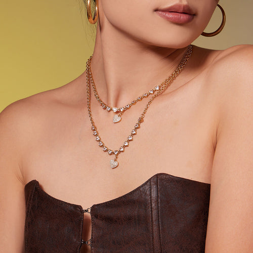 Model wearing two layered gold heart zircon station necklaces