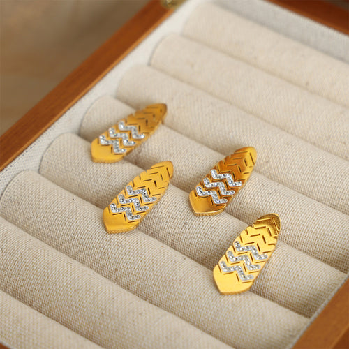 Four gold leaf chevron crystal studs on beige jewelry roll