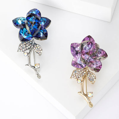 Front view of the crystal rose stem brooch in purple or blue with polished metal detail on a white background