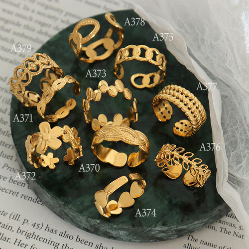 Labeled gold open ring styles A370-A379 arranged on green marble