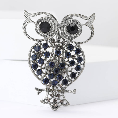 Blue rhinestone openwork owl brooch close-up on white background