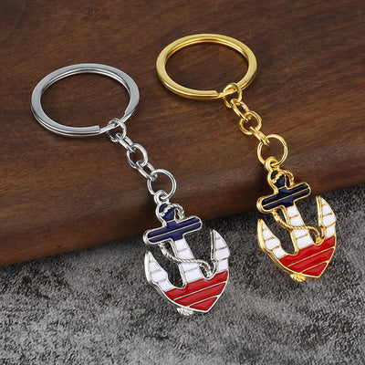 Gold-tone and silver-tone anchor keychains displayed side by side on wood.