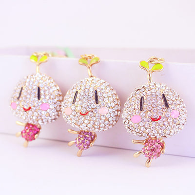 Three smiling sprout charms with clear rhinestone faces and pink or purple bodies.