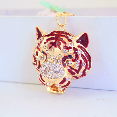 Close front view of the gold-tone tiger head with red enamel and clear stones.