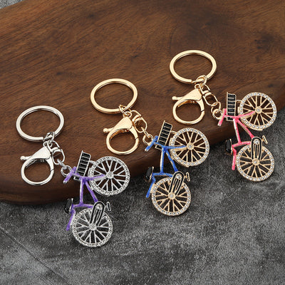 Multiple stone-accent bicycle keychains on gray fabric