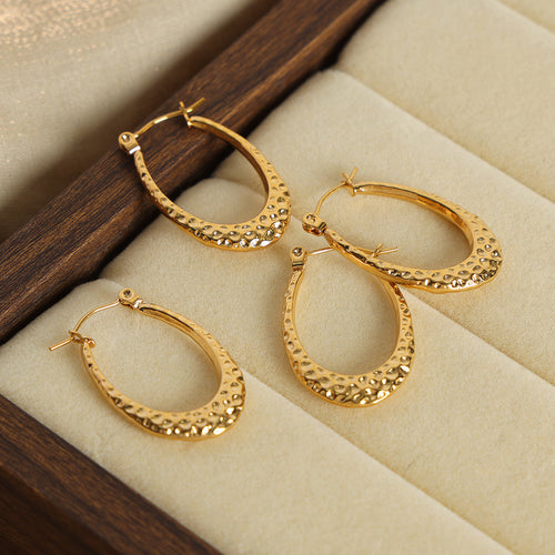 Three gold hammered teardrop hoops arranged in velvet jewelry box