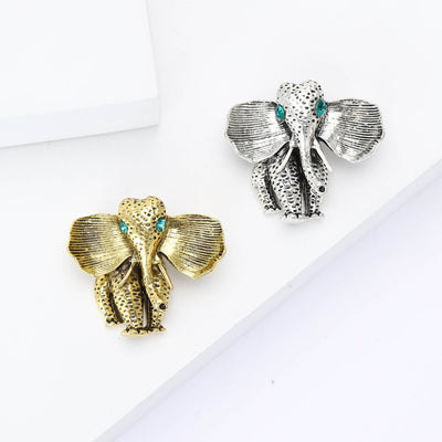 Silver Elephant, Antique Gold Elephant brooch styles arranged on a light display