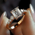 Emerald-Cut Clear Solitaire Ring With Round Side Stones In Gold Tone view 2