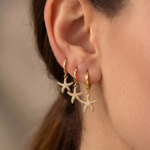 Ear stacked with three gold zirconia starfish huggie earrings