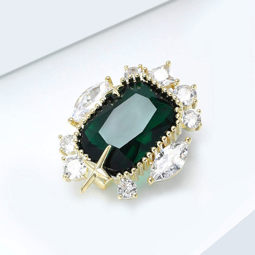 Emerald green gem brooch angled on white display surface