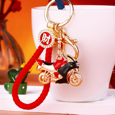 A front product view shows the jeweled motorcycle keychain with its visible ornament and hanging hardware.