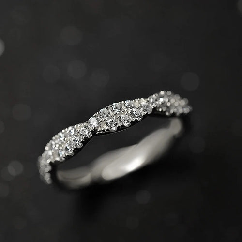 White gold tone twisted pave crystal ring on dark bokeh background