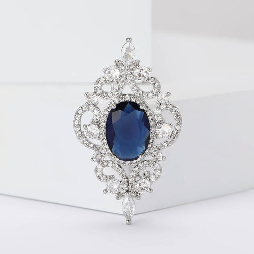 Blue oval center silver filigree brooch upright on white blocks