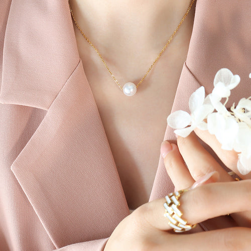 Gold single white faux pearl collarbone necklace on pink blazer