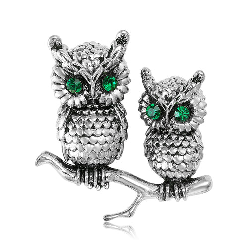 Two textured owls with green eyes perched on a branch shown in a styled display.