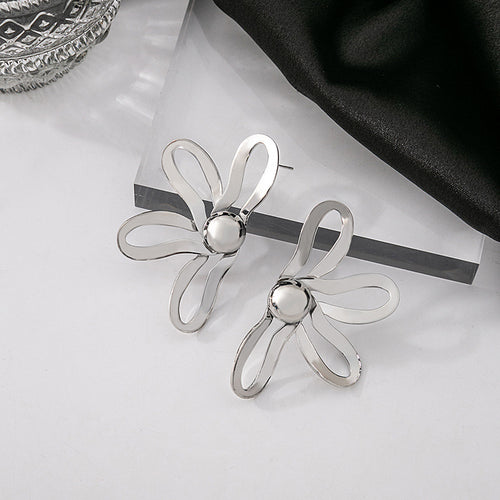 Silver openwork flower stud earrings pair on acrylic block with glass