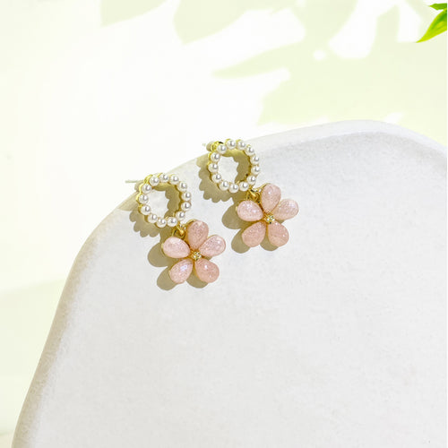 Pink glitter flower pearl ring drops on white stone display