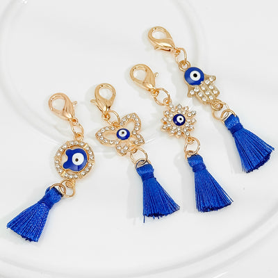 Four rhinestone evil eye tassel charms in different shapes laid out together