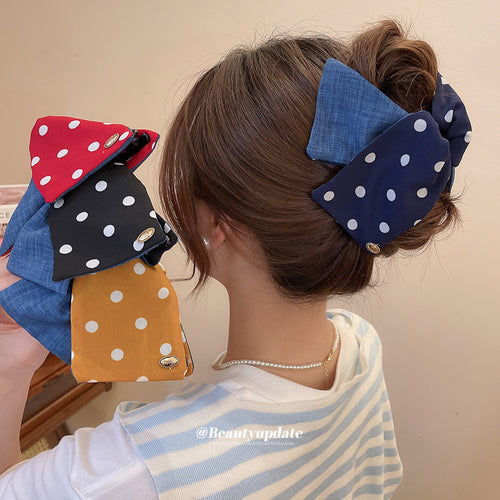 Woman in bun wearing navy polka scrunchie holding three more colorways