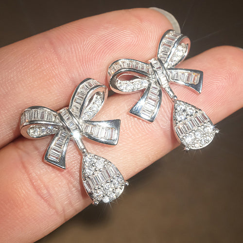 Silver bow drop earrings on fingers showing bright stone sparkle