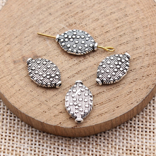 Dotted oval spacer bead arranged on a wood surface