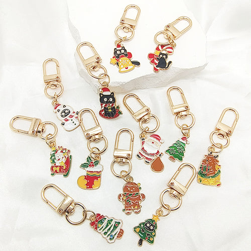 Twelve Christmas enamel charms with gold clasps arranged on white fabric