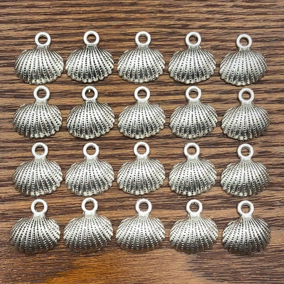 Antique silver shell charms arranged on a light background