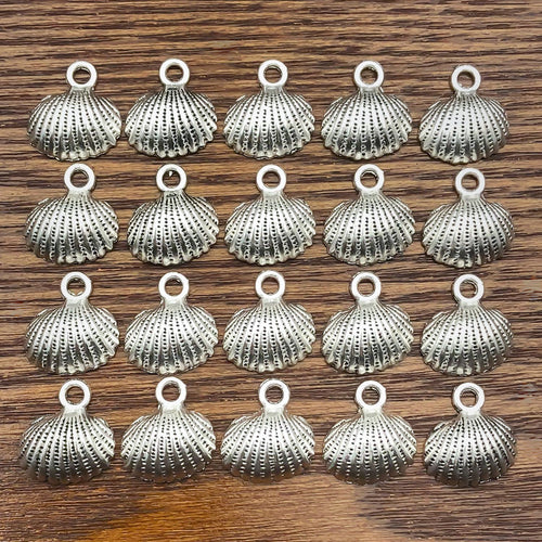 Antique silver shell charms arranged on a light background