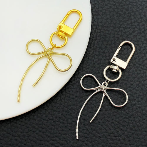 Alternate arrangement of the gold and silver rope bow metal clasp keychain design showing its hardware and charm details