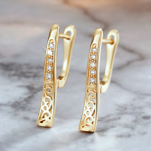Gold CZ line filigree huggie ear clips pair on marble surface