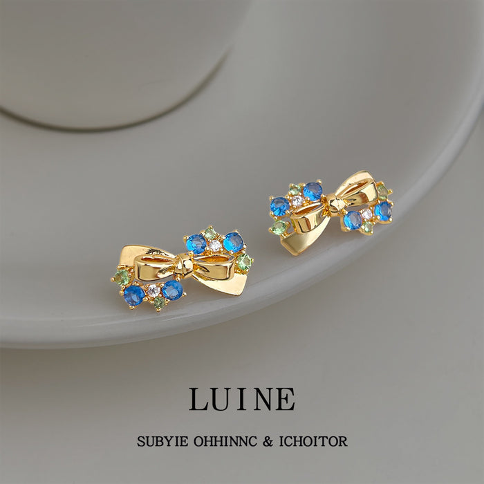 Gold Tone Ribbon Bow And Bright Blue Stone Stud Earrings For Women