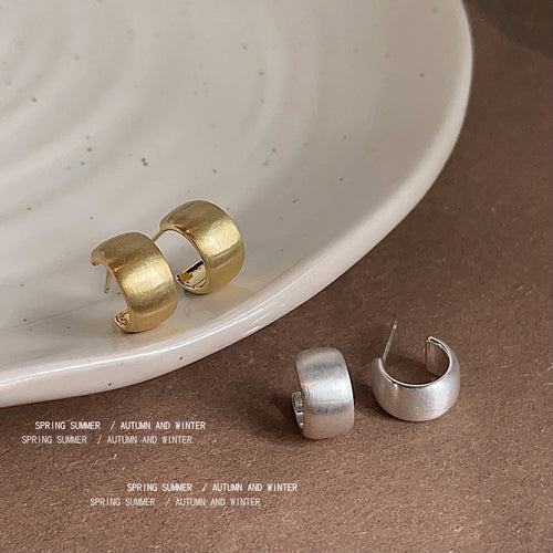 Gold and silver brushed matte half hoop studs on white plate and table
